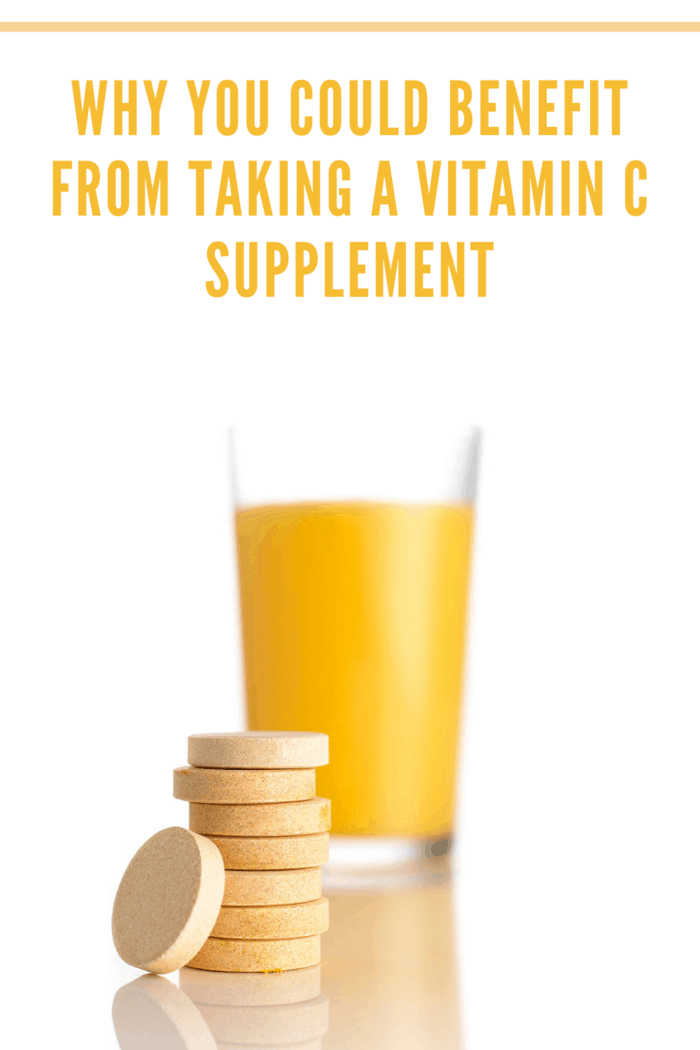 glass of orange juice with vitamin c supplements stacked in front