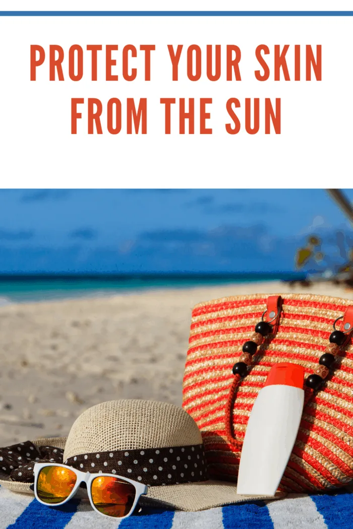 beach towel on beach with sunscreen, sun hat and sunglasses