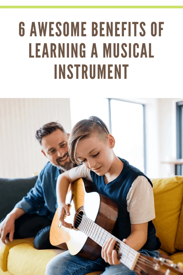 father teaching son to play guitar