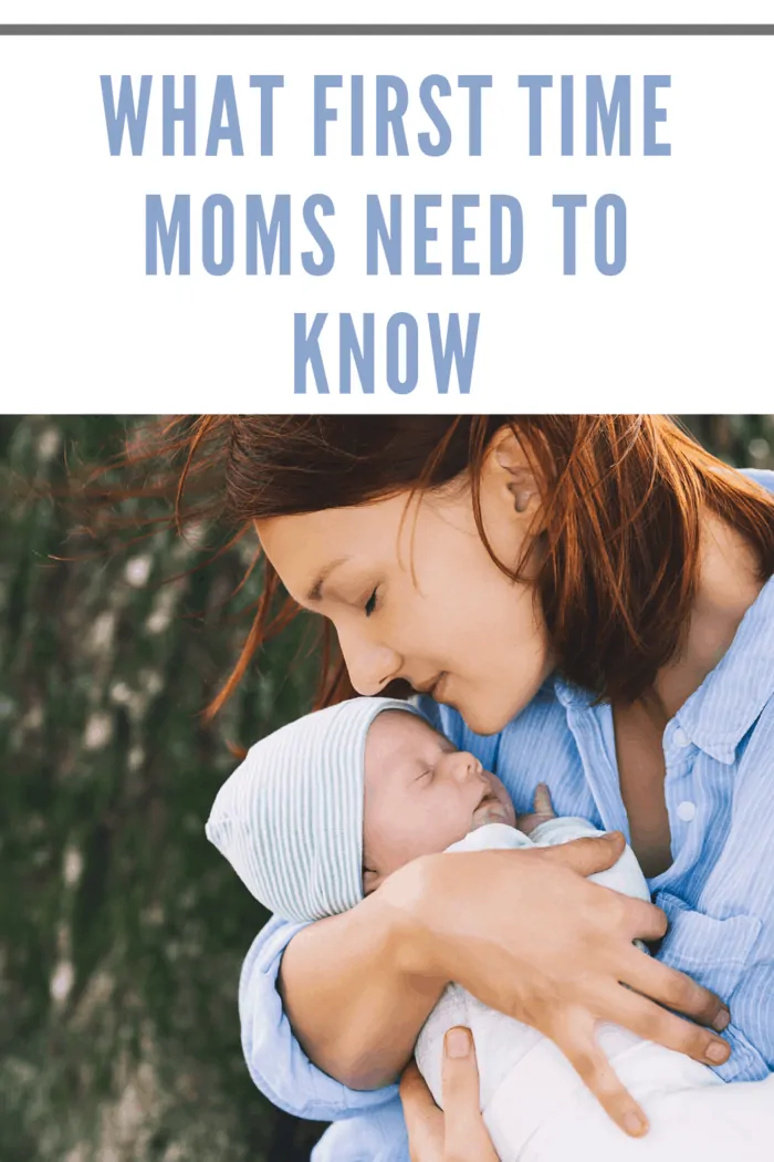 mom holding newborn in arms while outdoors