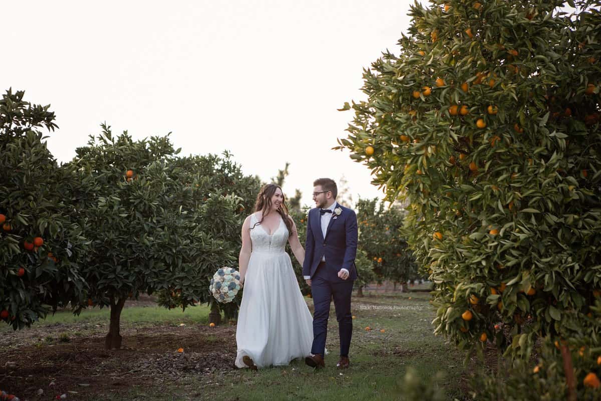 picture of the newly married couple, walking hand in hand through the orange grove as husband and wife.