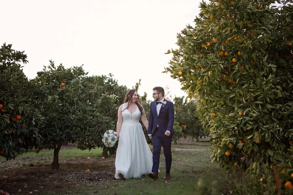 picture of the newly married couple, walking hand in hand through the orange grove as husband and wife.