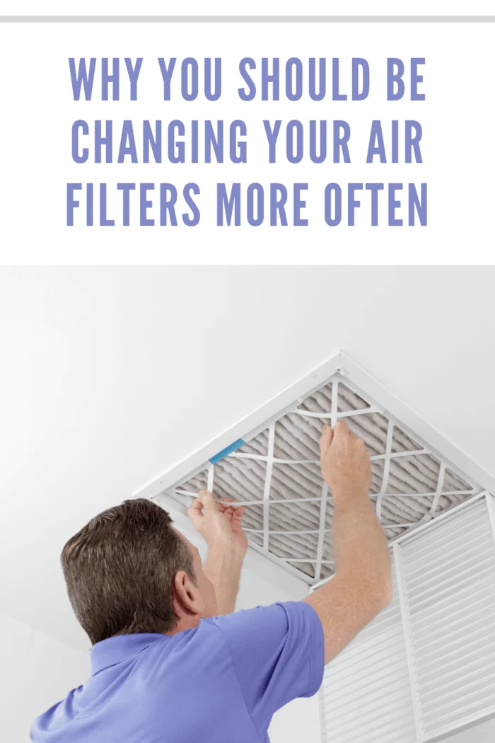 Caucasian male removing a square pleated dirty air filter with both hands from a ceiling air duct. Guy taking out an unclean air filter from a home ceiling air vent.