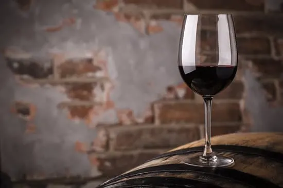 Glass of red wine standing on an oak barrel in a cellar