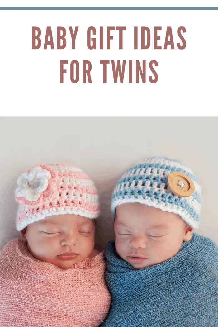 twin boy in blue blanket with blue and white hat next to twin girl wrapped in pink blanket and pink and white hat.
