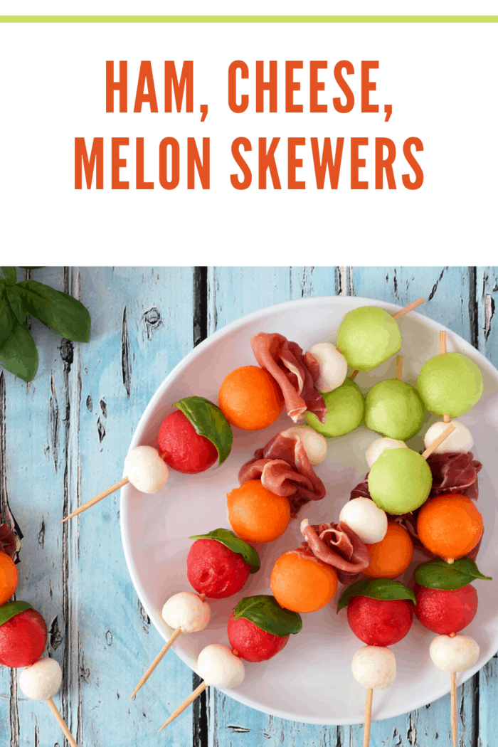 Ham, Cheese, Melon skewers-Plate of delicious summer fruit skewers with melon, cheese and prosciutto on a rustic blue wood background Image