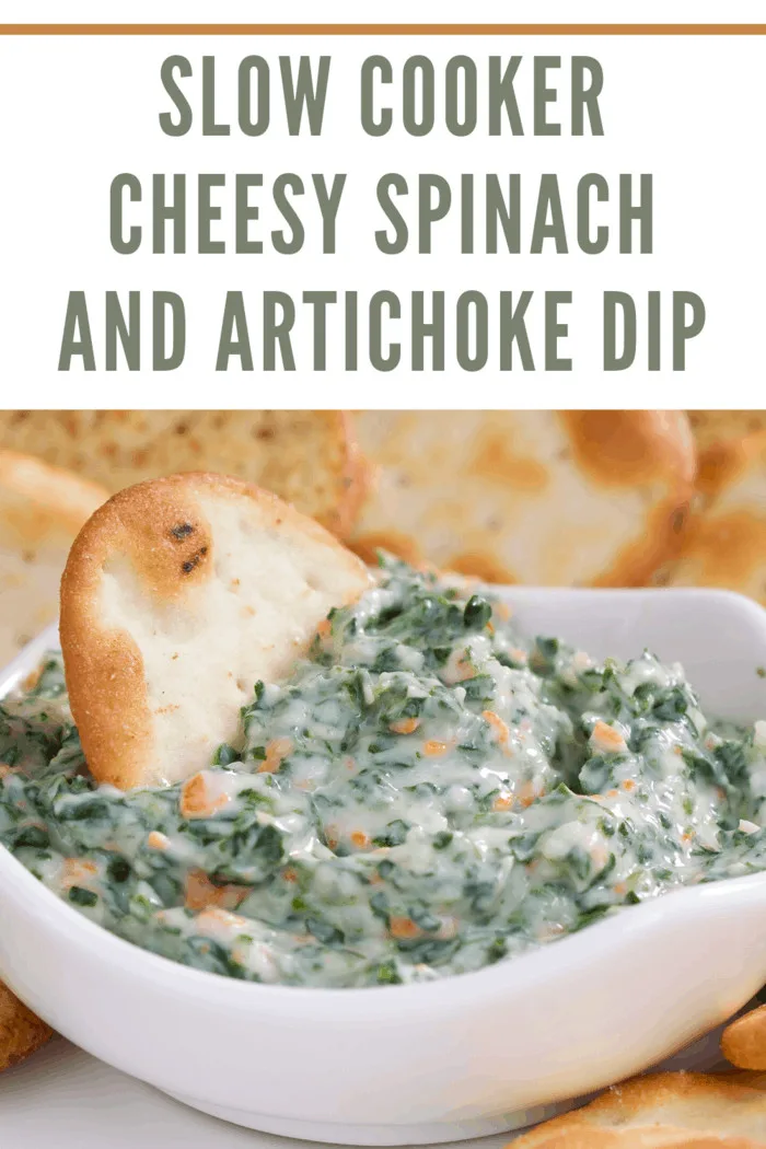 Slow cooker cheesy spinach and artichoke dip served in a white bowl with a toasted bread slice