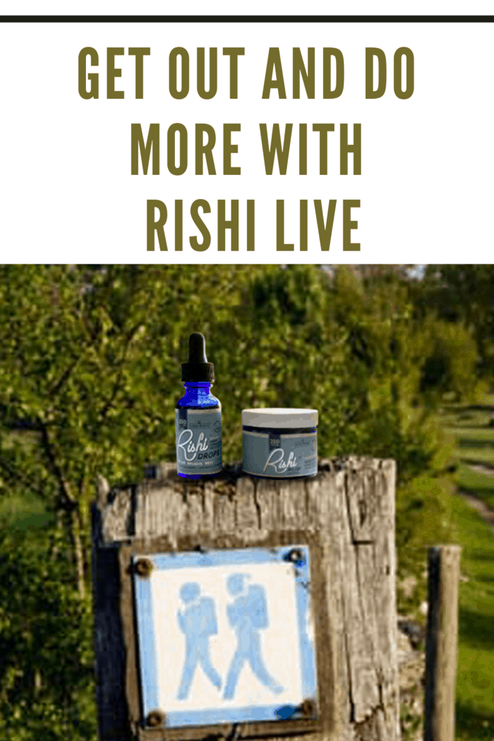 rishi rub and rishi drops sitting on a fence post above a hiking sign in the woods.