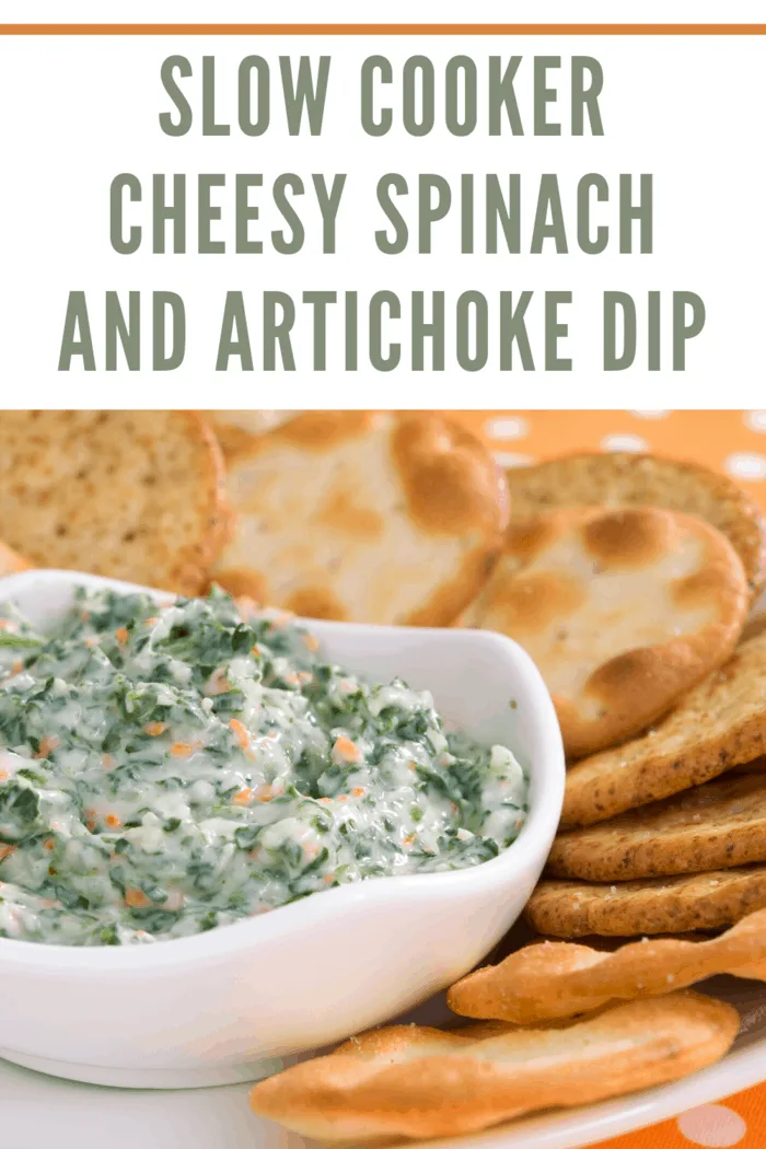 Slow cooker spinach artichoke dip in a bowl, garnished with fresh herbs and served with tortilla chips