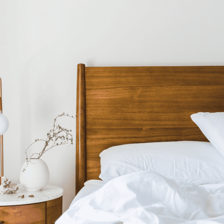 wooden headboard with bed with white sheets crumpled after being slept in