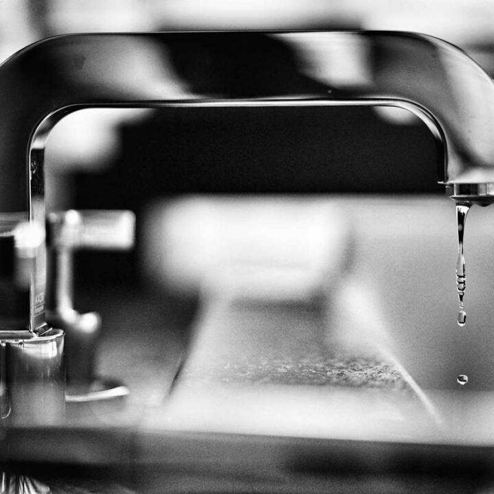 black and white photo of kitchen faucet dripping water