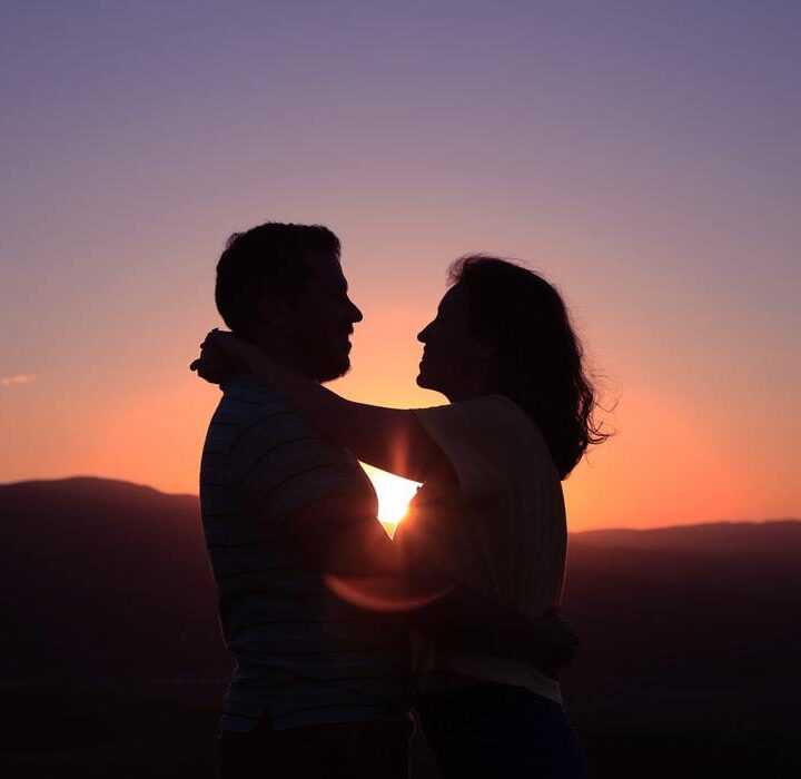sunset with silhouettes of husband and wife hugging