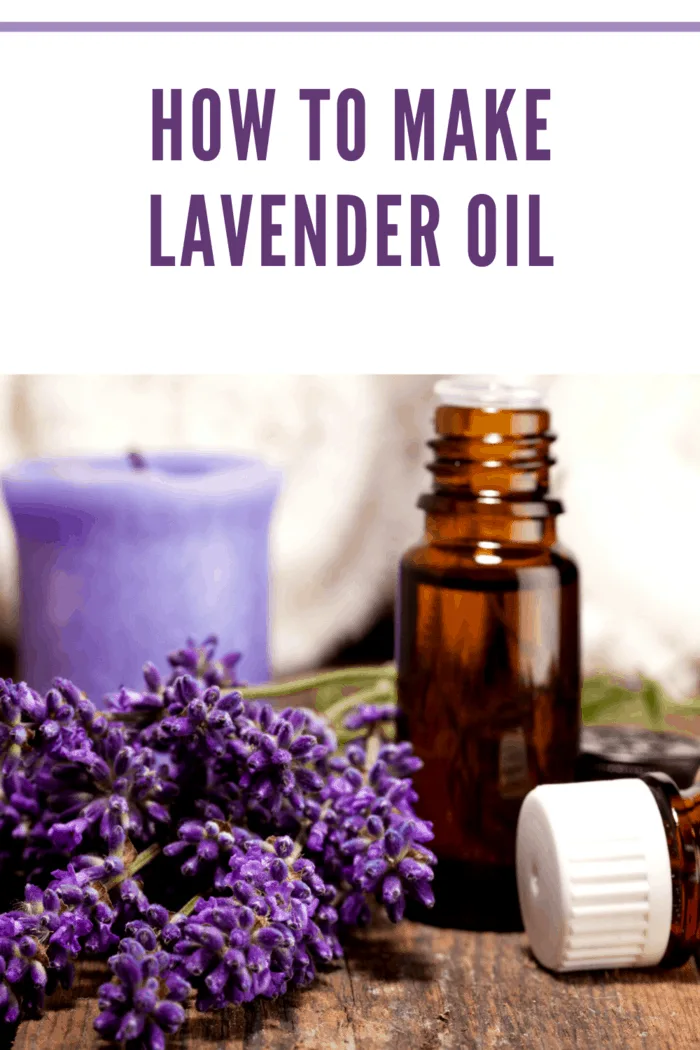 Amber glass bottle of lavender essential oil with fresh lavender flowers and a purple candle in the background on a wooden surface.