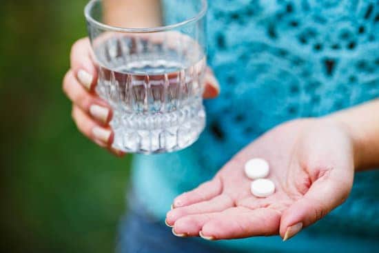 the girl holds a glass of clean water and two white pills