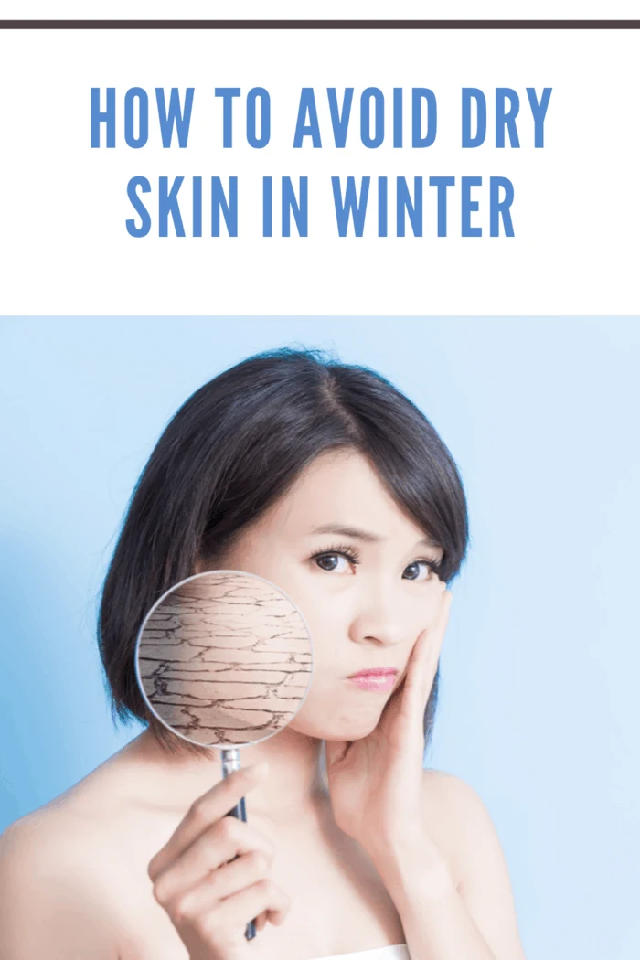 asian woman holding up magnifying glass showing dry skin in winter