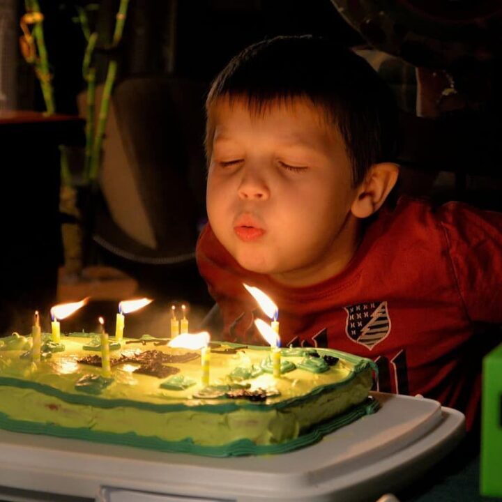 young boy blowing out birthday candles on cake