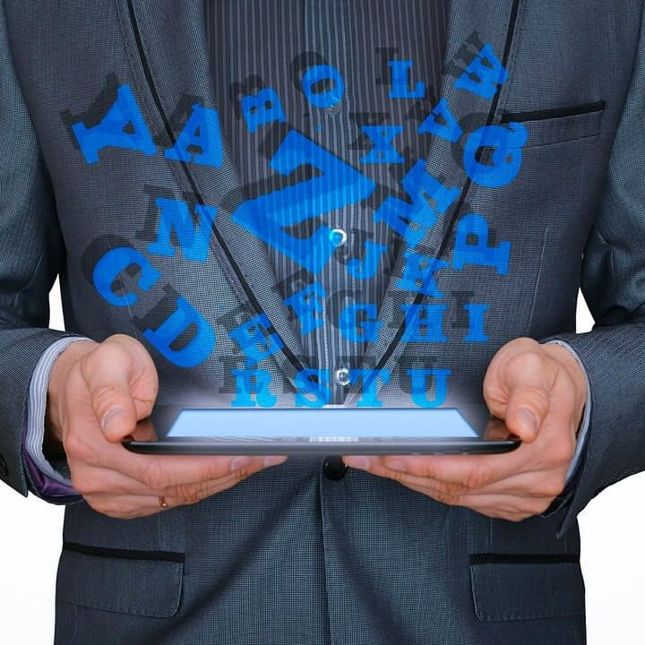 man in suit holding ebook with letters postitioned above ebook to represent learning a second language