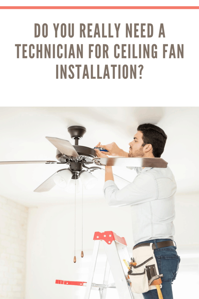 Attractive young technician stepping on a ladder and installing a ceiling fan