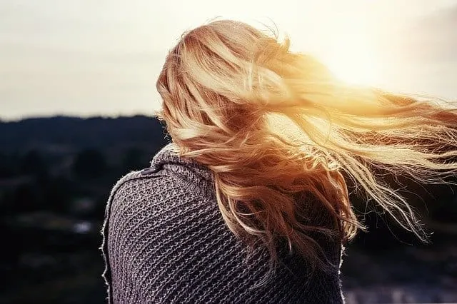 woman with blonde hair blowing in wind with grey sweater on