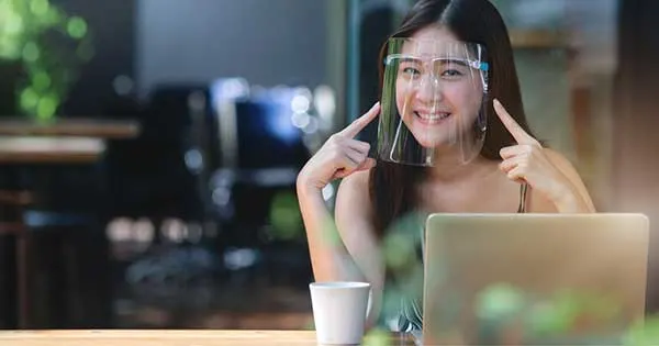 Pretty woman wearing face shield for healthcare, Young Asian woman sitting in coffee shop and working on laptop