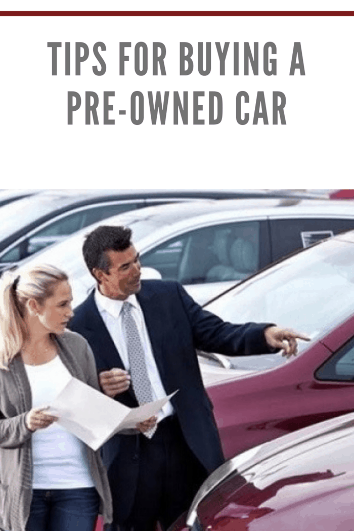 dealer walking car lot with woman interested in buying a pre-owned car