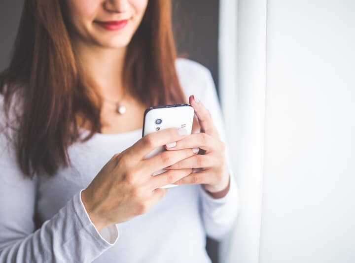 Close up portrait of a young woman typing a text message on mobile phone