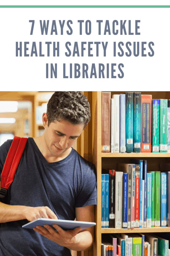 Student leaning against bookshelf holding a tablet pc at the library practicing safety issues