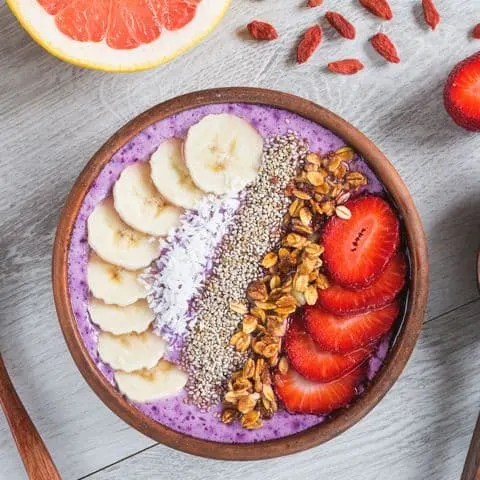 Acai smoothie bowl with superfoods. Smoothy bowl topped with banana, chia seed, coconut, strawberry and granola representing superfoods taking your skincare and beauty game to the next level