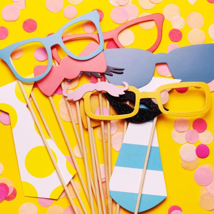 Photo booth props glasses, mustache, lips on a pink background flat lay. Birthday parties and weddings.