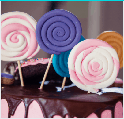 Close-up shot of swirl lollie candies arranged on a chocolate cake.