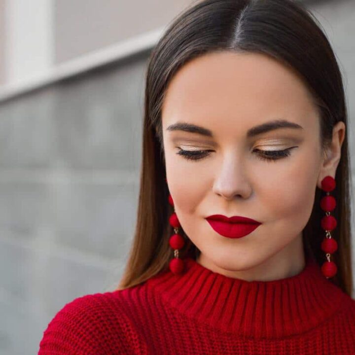 young woman perfecting young mother makeup routine with bold red lips