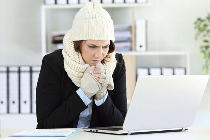 Cold angry executive working at office with a heater failure in winter
