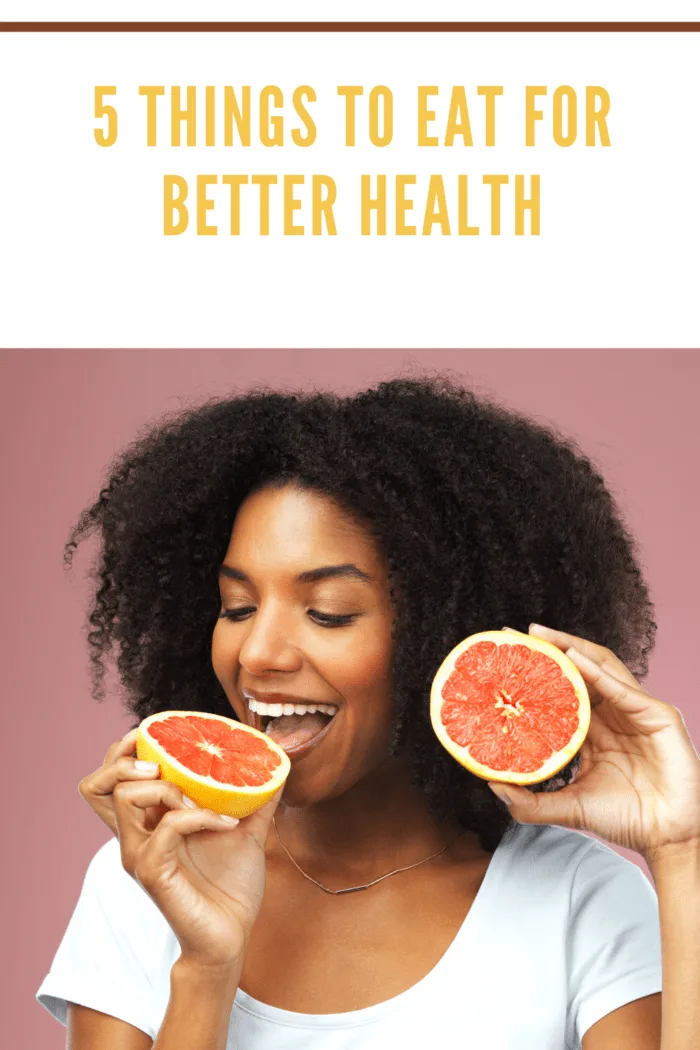 Studio shot of an attractive young woman eating grapefruit against a pink background