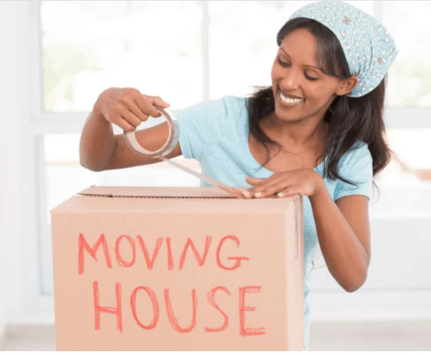 Smiling woman packing cardboard box for moving home.