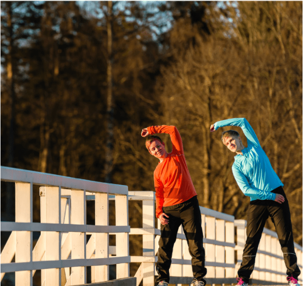 Two women stretch together on the bridge at sunrise