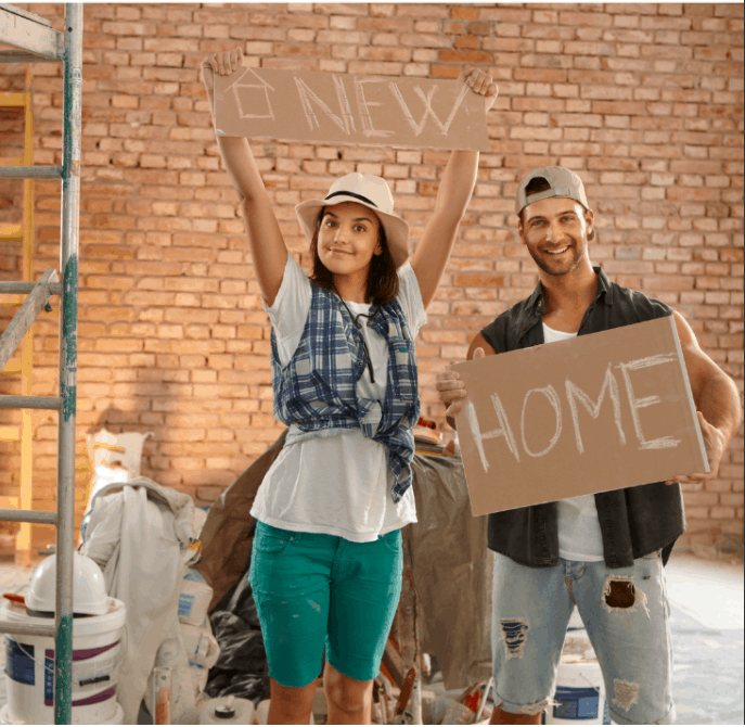 Young couple holding new home text at renovation site
