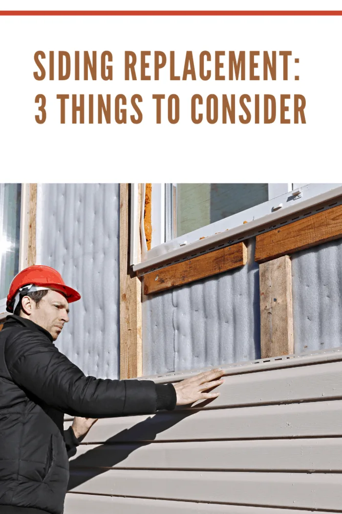 A worker installs panels beige siding on the facade of the house