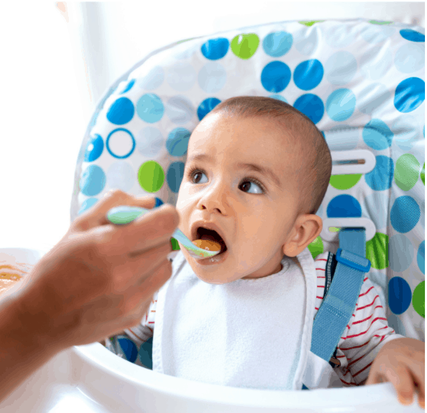 Caring parent taking responsibility of introducing her child to solid foods and teaching him that milk is not the only food in the world