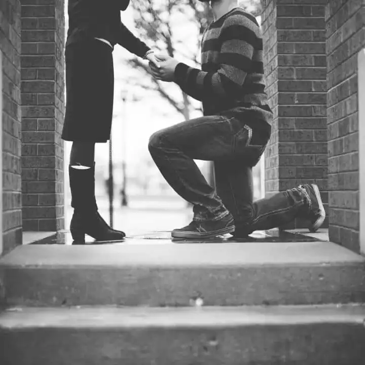 black and white photo of man on one knee proposing with engagement ring