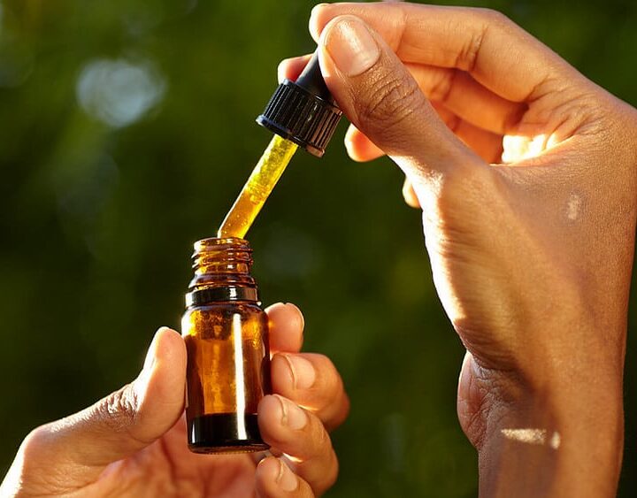 a dropper containing CBD oil in a woman's hand