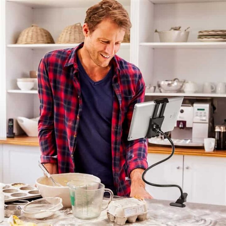 man reading recipe on tablet computer surrounded by kitchen gadgets