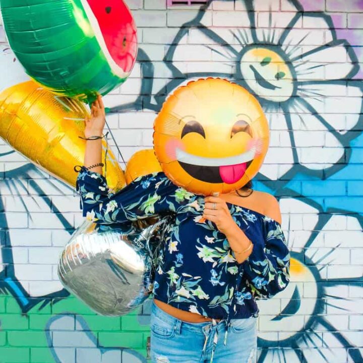 woman making a positive impact with her clothes using emoji mylar balloon for her face