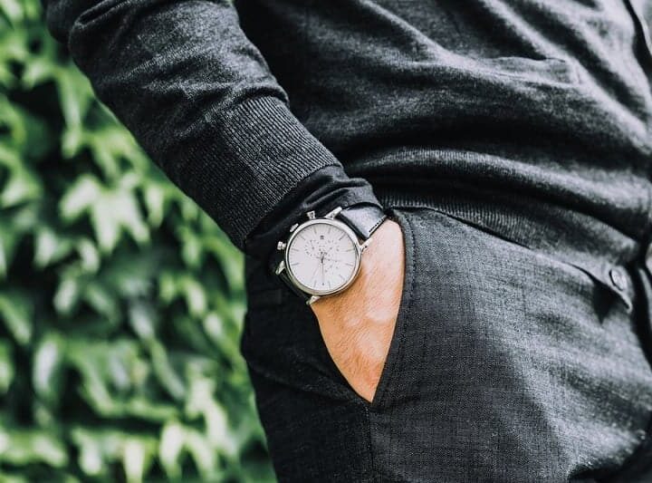 closeup fashion image of luxury watch on wrist of man.body detail of a business man.Man's hand in a grey shirt with cufflinks in a pants pocket closeup. Tonal correction
