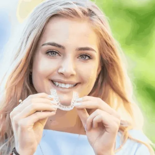 Invisalign orthodontics concept - Young attractive woman holding - using invisible braces or trainer.