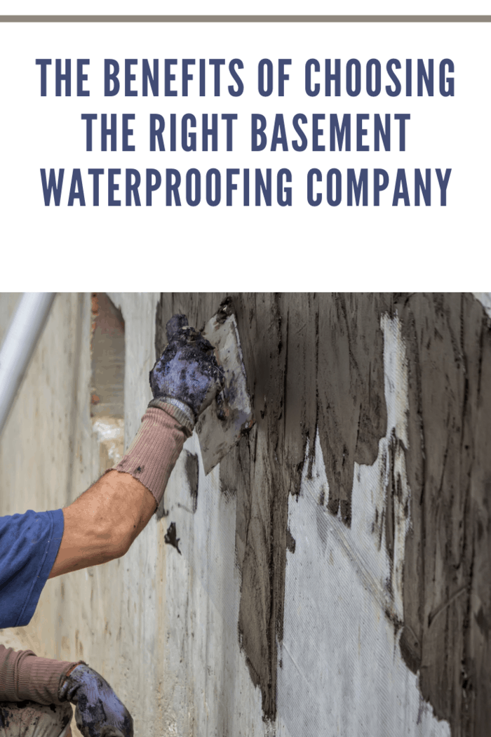 Exterior basement wall waterproofing, worker installing waterproofing tar sealer. Selective focus and motion blur.