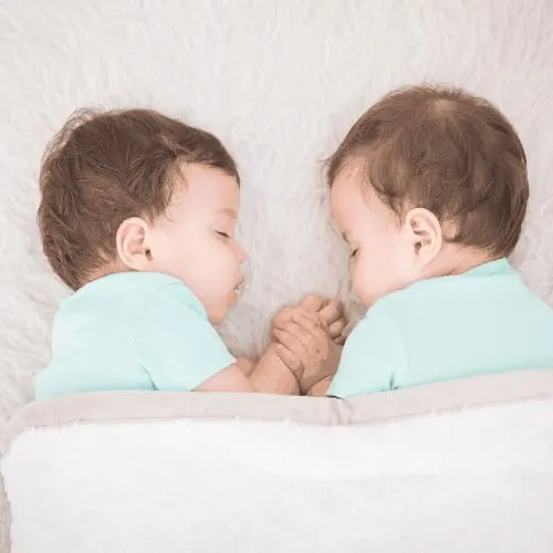 Newborn beautiful baby twins sleeping with pacifier. Closeup portrait, caucasian child