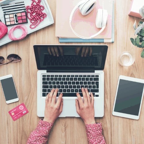 Fashion blogger working at office desk with a laptop: fashion, beauty and technology concept