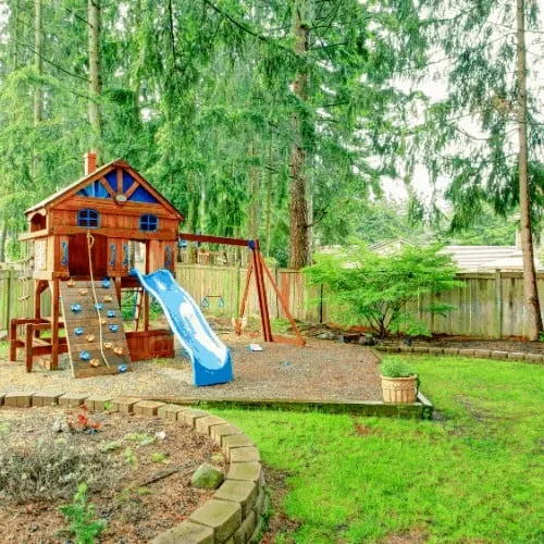 Fenced green backyard with playground for kids