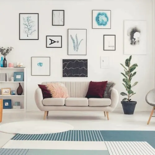 Modern living room interior with rugs, white sofa, ficus and posters on the wall.