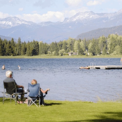 retired couple at lake enjoying view of mountains.